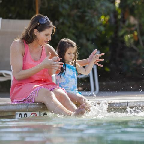 Mother and daughter on side of a pool
